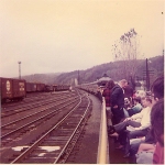 Open-air cars are coupled and occupied at the station